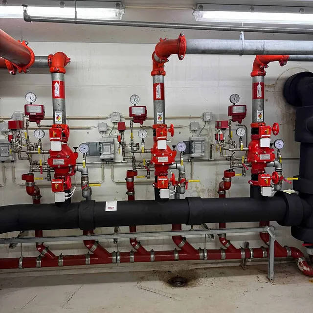 Flere sprinklerstiger montert på vegg med ventiler og måleinstrumenter.
